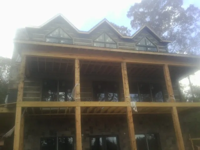 Dormers and porch framing on a large log home under construction — Roof Coating work by our crew in Cerro Gordo