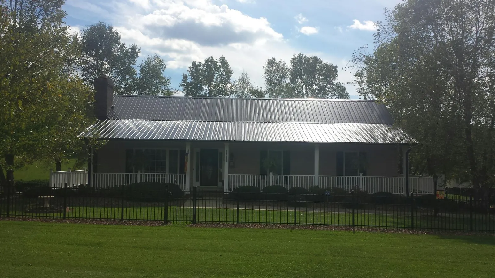 Gray metal roof on a brick ranch with a full width front porch — Gutter Guard Installation work by our crew in Cerro Gordo